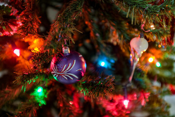Festive christmas background. Multi-colored lights and balls on the branches of spruce. Blurry lights at night. Decorated Christmas tree on blurred background.