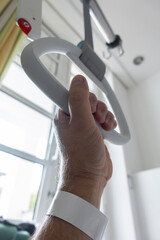 Krankenbett im Krankenhaus, Hand an einer Aufrichthilfe, Triangel, Haltegriff