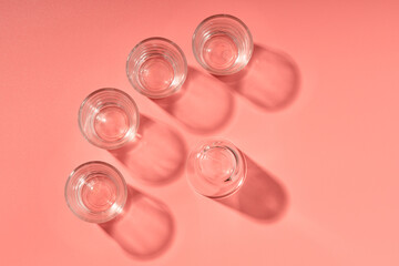 five empty glass glasses on a pink background, top view of the glasses for alcohol