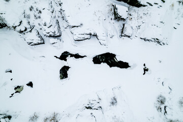 top view of the river with thawed ice, holes on the ice on the river. rocks and snow