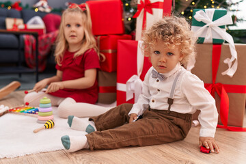 Adorable boy and girl playing with xylophone and car toy celebrating christmas at home