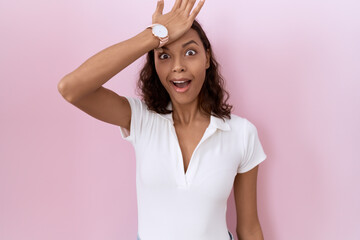 Young hispanic woman wearing casual white t shirt surprised with hand on head for mistake, remember...