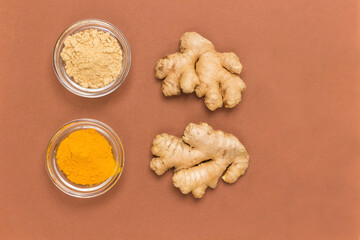 Ginger root, dry ginger, turmeric and rosemary sprig. Brown background.