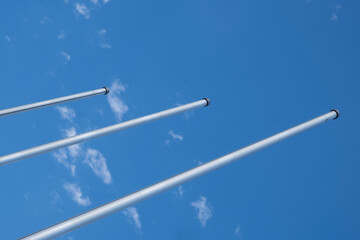 three empty flagpoles against a blue sky