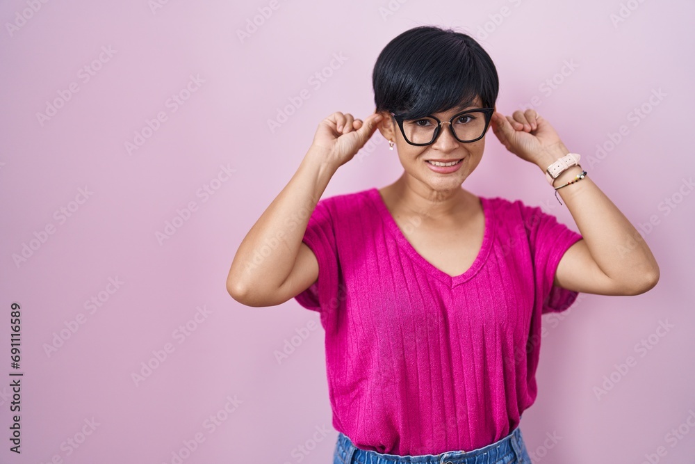 Canvas Prints Young asian woman with short hair standing over pink background smiling pulling ears with fingers, funny gesture. audition problem