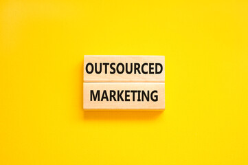 Outsourced marketing symbol. Concept words Outsourced marketing on beautiful wooden blocks. Beautiful yellow table yellow background. Business Outsourced marketing concept. Copy space.