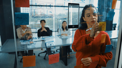 Smart hispanic businesswoman present marketing strategy to diverse manager team. Beautiful successful leader thinking while looking at sticky notes on glass board. Grow to success. Manipulator. - obrazy, fototapety, plakaty
