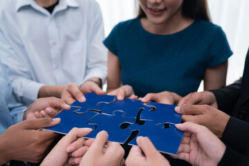 Diverse corporate officer workers collaborate in office, connecting puzzle pieces to represent...
