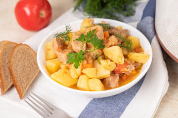 Beef, meat, stewed with potatoes, carrots, tomatoes and spices in modern multi cooker on kitchen table. Cooking stewed potatoes with meat in multicooker.