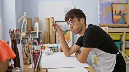 Captivating glimpse into a young hispanic man's world, artist, brush in hand, lost in thought while...