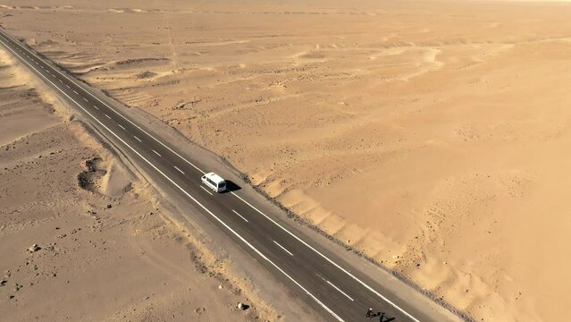 Turistas em furg&atilde;o parados no meio do deserto com apenas uma estrada &agrave; vista.