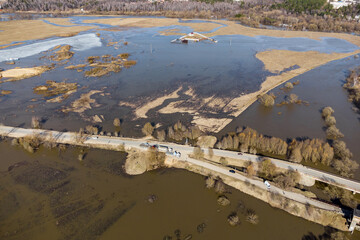 Aerial view of the road and a partially flooded floodplain field during the spring flood of the river