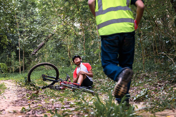 Mountain Bike Accident Cyclist Falls and Suffers Injury in Practice Activities Cycling Sports in Natural Park, Urgent Aid Required from First Aid Staff Assistant.