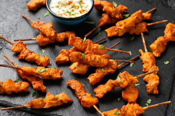 Grilled chicken fillet on skewers with white sauce on rustic stone board
