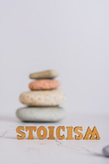 Concept stoicism word made from letters and pyramid of stones on gray background vertical view