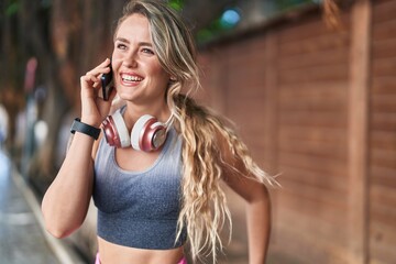 Young blonde woman wearing sportswear talking on smartphone at street - Powered by Adobe