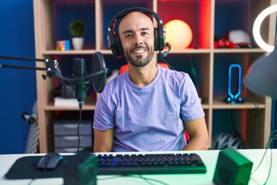 Middle age bald man playing video games wearing headphones with a happy and cool smile on face. lucky person.