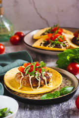 Smash Burger Tacos with beef patty, tomatoes and herbs on a plate vertical view