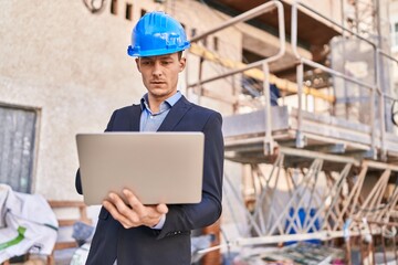 Young man architect using laptop at street