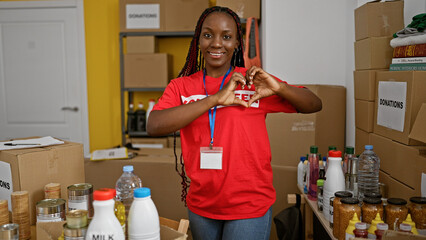Confident african american woman volunteer with braids and a beaming smile making a heart gesture...