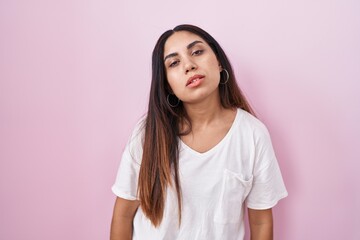 Young arab woman standing over pink background looking sleepy and tired, exhausted for fatigue and hangover, lazy eyes in the morning.