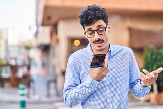 Young caucasian man talking on the smartphone with serious expression at street