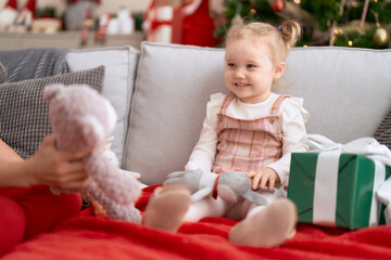 Adorable caucasian girl sitting on sofa by christmas tree at home - Powered by Adobe