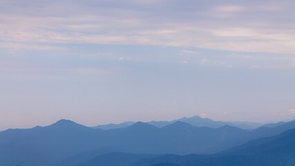 Fog and clouds in the mountains against the backdrop of the setting sun, changeable weather in the mountains, clouds and nebula on mountain peaks