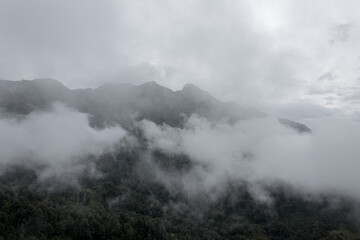 Fog and clouds in the mountains against the backdrop of the setting sun, changeable weather in the...