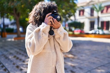 Young beautiful hispanic woman using professional camera at park