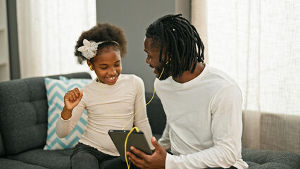 African american father and daughter smiling confident listening to music at home