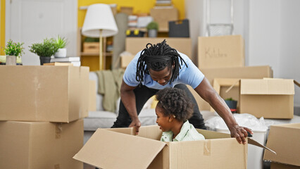 African american father and daughter playing with cardboard box at new home