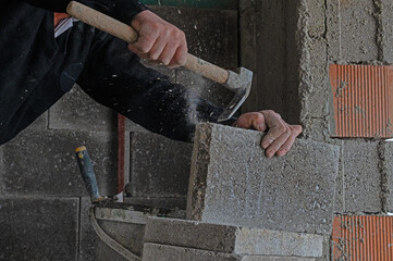 The builder is chiselling bricks with a chisel.