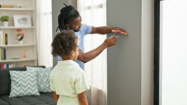 African american father and daughter smiling confident measuring height on wall at home