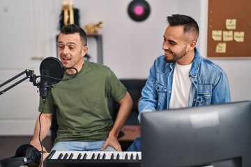 Two men musicians singing song playing piano at music studio