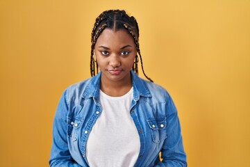 African american woman with braids standing over yellow background depressed and worry for distress, crying angry and afraid. sad expression.