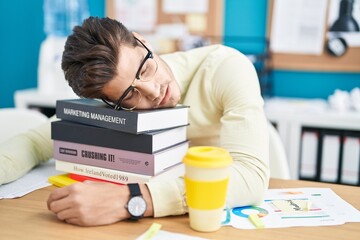 Young hispanic man business worker leaning on books sleeping at office - obrazy, fototapety, plakaty