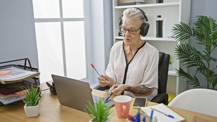 Jovial senior grey-haired business woman tapping into the rhythm at work, gleefully drumming her...