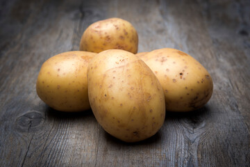 potatos in a pile on a wooden surface, uncooked
