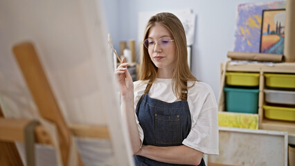 Young blonde woman artist looking draw thinking at art studio