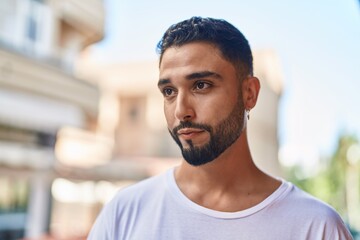 Young arab man looking to the side with serious expression at street