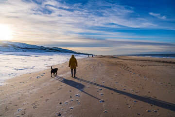 Spaziergänger mit Hund am Strand von Westerland auf Sylt im Winter