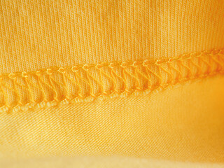 Stitched seam on yellow fabric textile background close-up selective