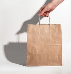 Hand taking kraft bag, paper package for delivery, shopping