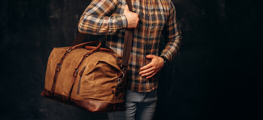 Man Holding His Canvas Travel Bag. Medium shot of an athletic man with his dark brown canvas duffle...