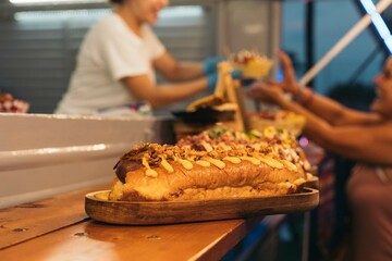 Giant hot dog displayed on a shelf of a food truck. Freshly made fast food at an outdoor festival at night.