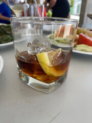 Glass with a drink, ice and lemon the table