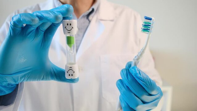 Explore the world of dental care with a professional touch. This video showcases a doctor dentist confidently holding a toothbrush and hourglass, emphasizing the importance of timely oral health. 
