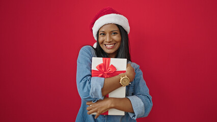 African american woman hugging christmas gift over isolated red background