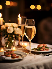 Fototapeta na wymiar Romantic dinner table with two glasses of champagne and food, blurry lights background and candle light